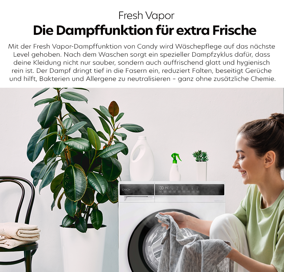 Feature-Banner,Frau faltet graues Kleidungsstück vor weißer Candy-Waschmaschine mit Dampffunktion, daneben große grüne Zimmerpflanze und weiße Flaschen.'