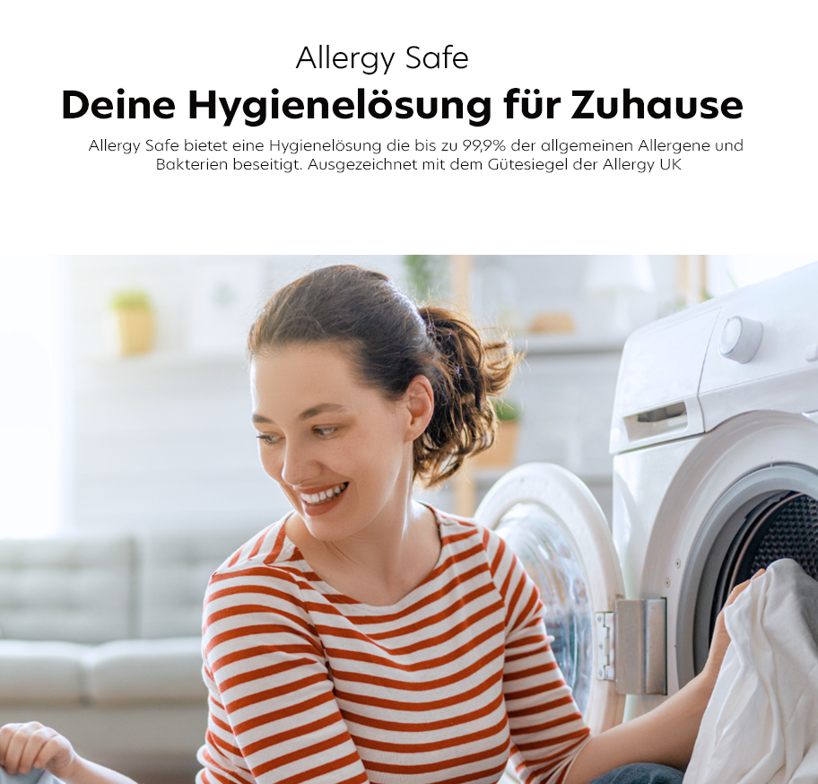 Feature-Banner, Frau mit gestreiftem Shirt sitzt neben geöffneter Waschmaschine in hellem Wohnzimmer.'