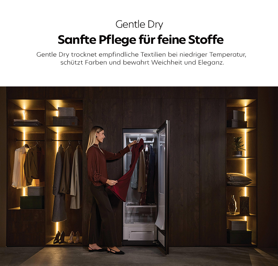 Feature-Banner, Frau entnimmt Kleidungsstück aus offenem Haier Gentle Dry Wäschetrocknerschrank in modernem, dunklem begehbarem Kleiderschrank mit indirekter Beleuchtung.'