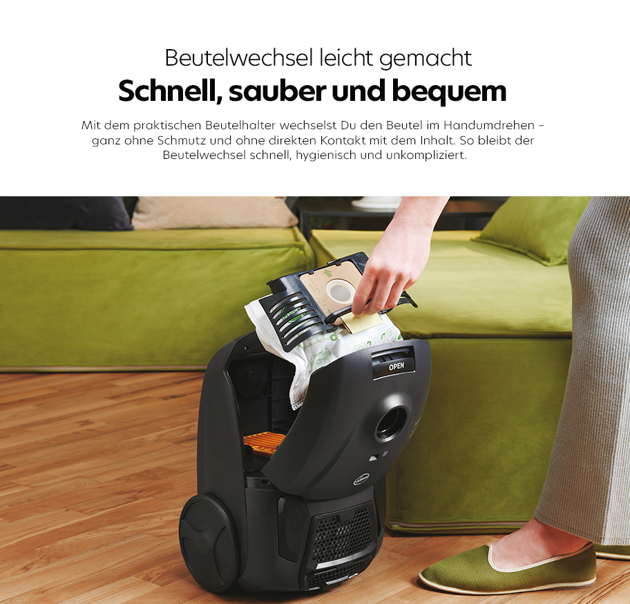 Feature-Banner, Hand wechselt Staubsaugerbeutel im geöffneten schwarzen Staubsauger vor grünem Sofa, Text über Beutelwechsel leicht gemacht, schnell, sauber und bequem.'