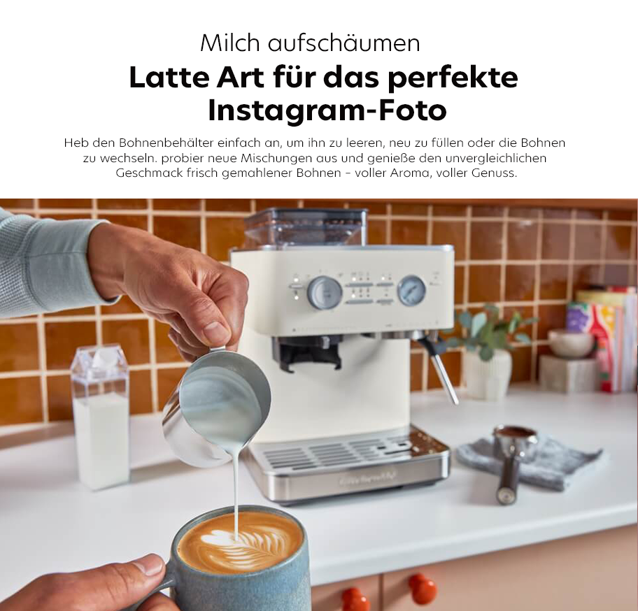 Feature-Banner, Kitchenaid Milchaufschäumer in einer modernen Küche. Eine Person gießt aufgeschäumte Milch in eine Tasse mit Latte Art. Sichtbare Kaffeeküche mit Espressomaschine und Kaffeebohnen.'