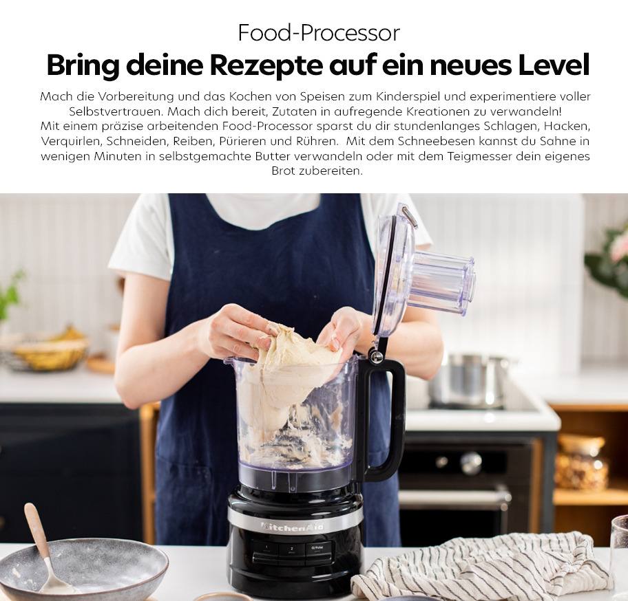 Feature-Banner, Küchenmaschine mit transparentem Behälter, in den eine Person Teig mit beiden Händen gibt, auf Küchenarbeitsplatte mit Schüssel und Geschirrtuch.'