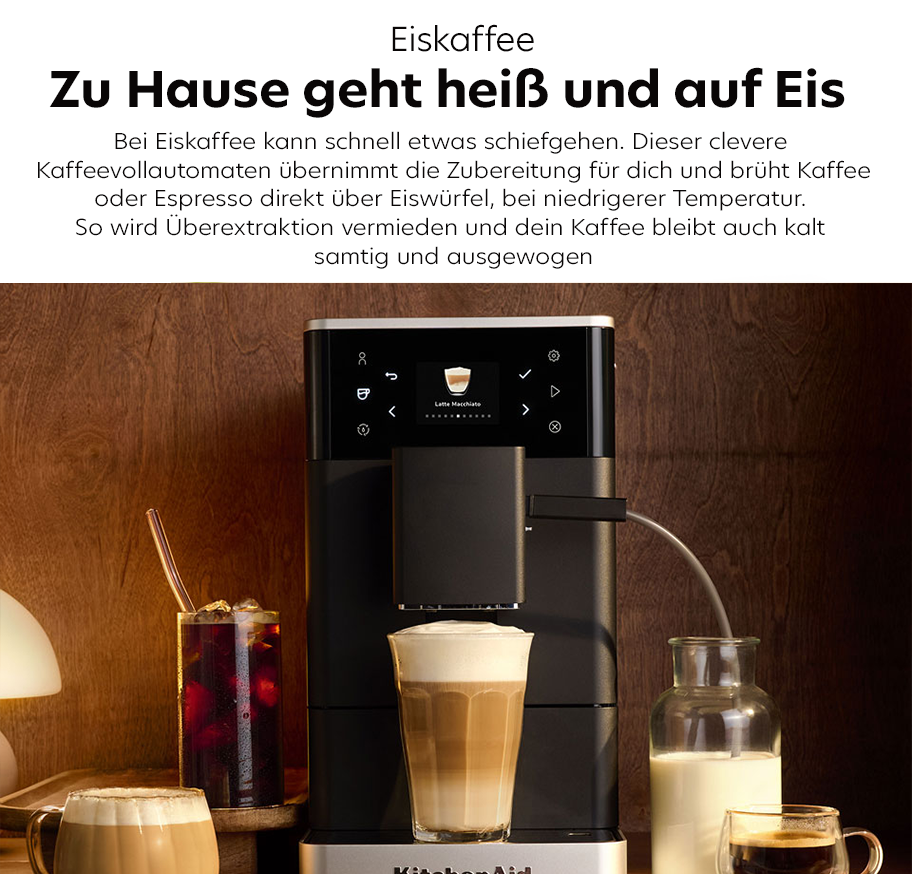 Feature-Banner, Kitchenaid-Kaffeevollautomat mit Latte-Macchiato auf der Abtropffläche, umgeben von Gläsern mit Eiskaffee und Milch in einem warm beleuchteten Raum.