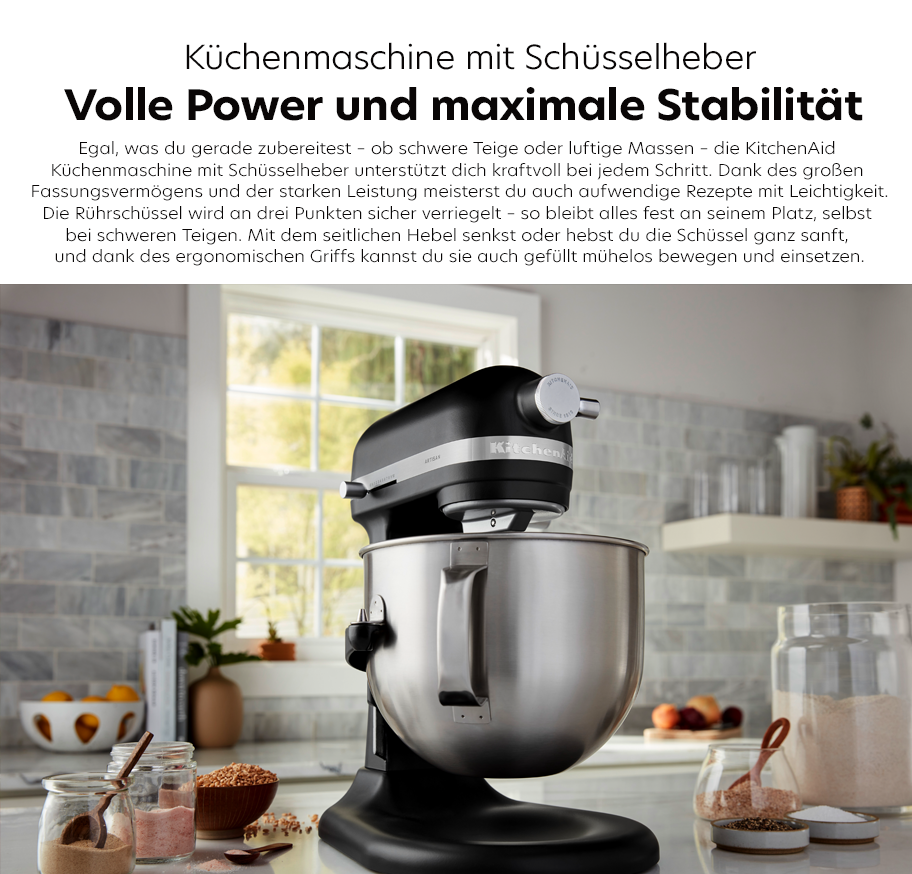 Feature-Banner, Küchenmaschine von KitchenAid mit Schüsselheber, schwarz, auf einer Arbeitsfläche. Im Hintergrund steht eine Schüssel und Zutaten sind sichtbar'.