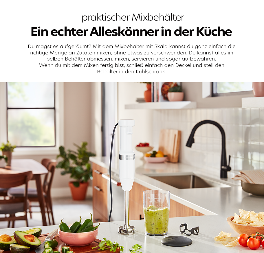 Feature-Banner, Weißer Mixbehälter mit Skala, Stabmixer und Deckel auf Küchenarbeitsplatte, umgeben von frischem Gemüse und Küchenutensilien.'
