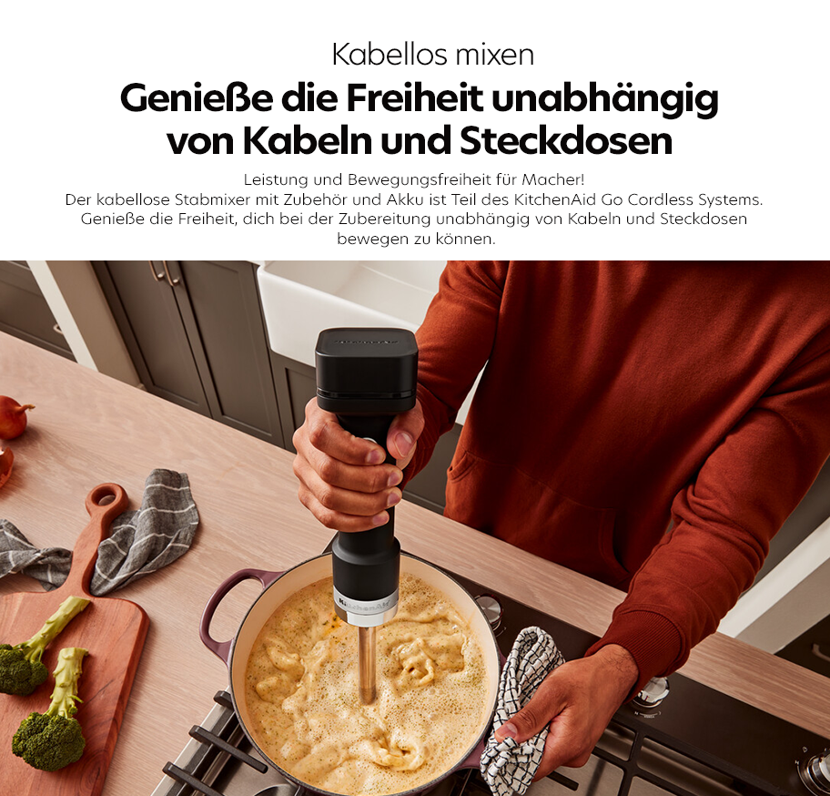 Feature-Banner, Person hält schwarzen kabellosen Stabmixer mit Akku über einen Topf mit schäumender Suppe auf einem Herd, Küchenutensilien und Gemüse liegen auf der Arbeitsplatte.'