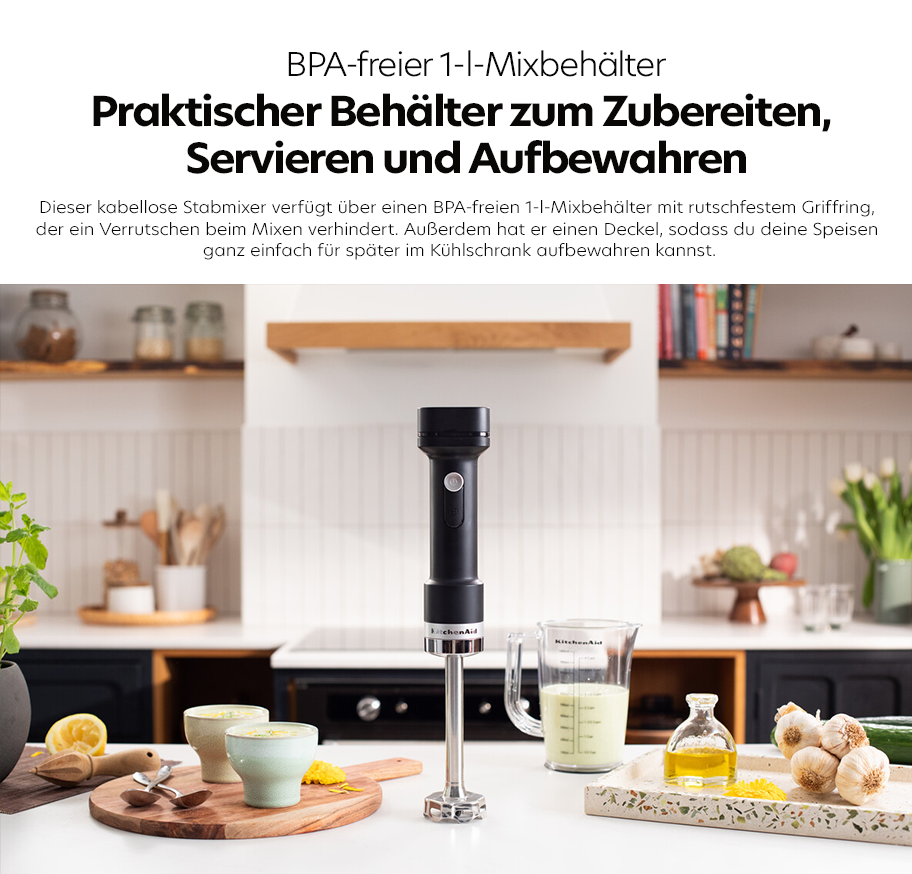 Feature-Banner, Kabelloser schwarzer Stabmixer mit Edelstahl-Mixbehälter und BPA-freiem 1-Liter-Mixbehälter auf weißer Küchenarbeitsplatte, umgeben von Küchenutensilien und Zutaten.'