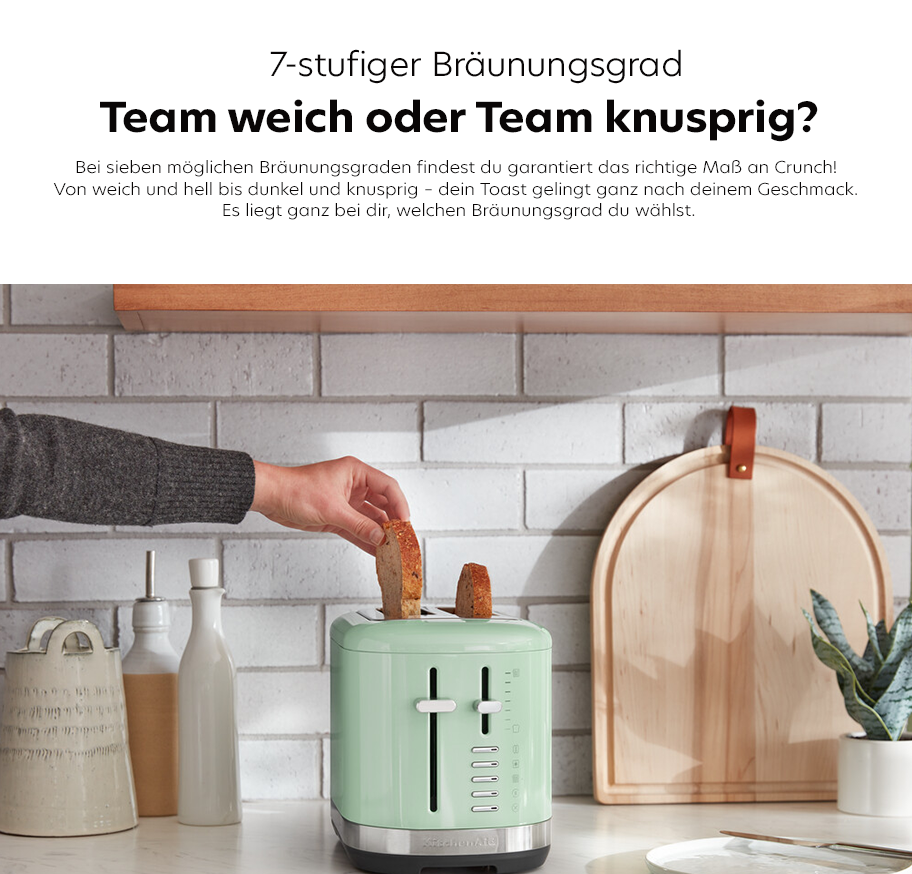Feature-Banner, Küchenzeile mit hellgrünem Pistazien-Toaster, Hand legt Toastscheibe ein, weiße Fliesenwand, Keramikgefäße, Holzbrett und Pflanze im Hintergrund.'