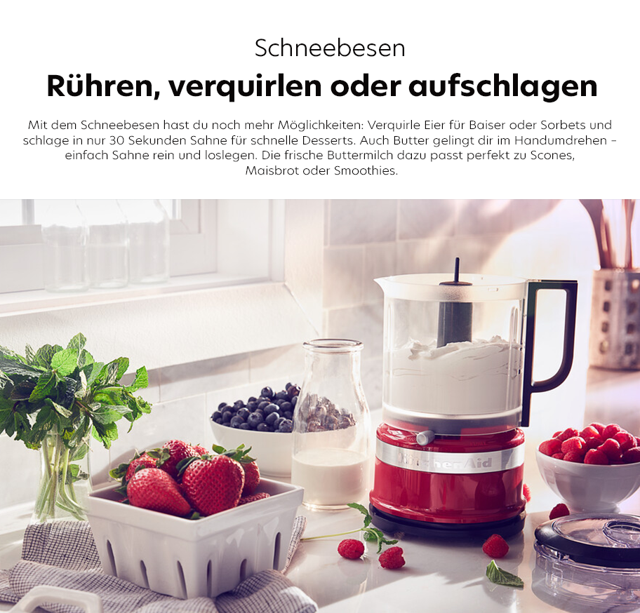 Feature-Banner, Roter KitchenAid-Schneebesen mit transparentem Behälter auf Küchenarbeitsplatte, daneben Schale mit Erdbeeren, Glasflasche mit Milch, Schale mit Himbeeren und frische Minzblätter.'